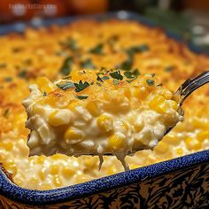 a spoon full of macaroni and cheese with parsley on top, in a blue dish