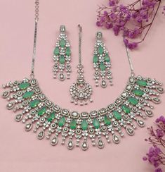 Embrace the feeling of elegance with our Fariba Necklace Set, a must-have from our Royal Heritage collection that combines luxury and grace. Carefully crafted, this stunning necklace set embodies the perfect blend of American chic and Indian artistry. The dazzling colors of the stones effortlessly blend together, adding a touch of opulence to any outfit. From its refined elegance to its cross-cultural charm, this set makes a statement of timeless beauty for every occasion. Handcrafted Metal: Metal Alloy Necklace Set includes necklace, earrings & headpiece Stone: Pearls, Premium American Diamond Stones (faux) Size: One Size Fits All, Adjustable Earrings: L-16CM Weight: 180 grams Made to Order: 2 Week Delivery Time Opulent Hand Set Necklace For Gift, Elegant Emerald Kundan Necklace For Gift, Exquisite Necklaces With Sparkling Stones For Celebration, Luxury Jewelry For Party With Stone Setting, Exquisite Cubic Zirconia Jewelry For Festive Season, Exquisite Festive Cubic Zirconia Jewelry, Elegant Hand-set Emerald Bridal Necklace, Silver Kundan Necklace With Hand-set Emeralds, Elegant Gemstone Jewelry Sets For Celebration