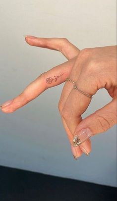 a woman's hand with a small tattoo on it and a ring in the middle