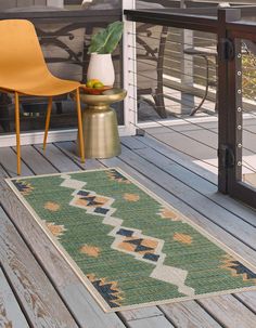 a green and yellow rug sitting on top of a wooden floor next to a chair