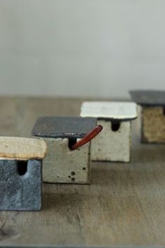 four cement blocks with different shapes and sizes on a wooden surface, one has a piece of wood sticking out of it