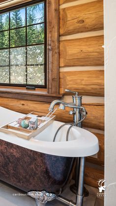 an old fashioned bathtub in a rustic bathroom with wood paneling and glass windows