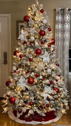 a white christmas tree with red and silver ornaments