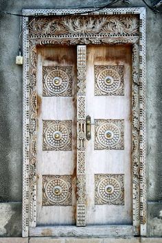 an old wooden door with intricate carvings on the front and side doors are painted white