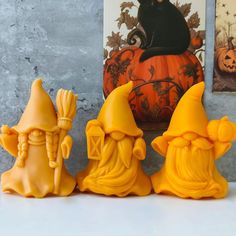 three yellow gnome figurines sitting next to each other on a white counter top