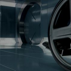 the wheel of a vehicle is shown in front of an abstract wall and floor pattern