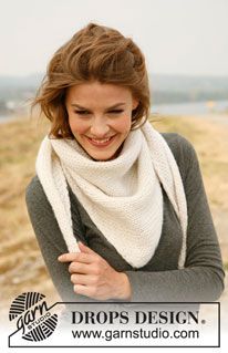 a smiling woman wearing a white scarf on top of a beach next to the ocean