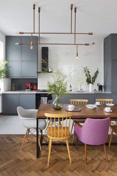 a dining room table with chairs and a vase on it in front of an open kitchen