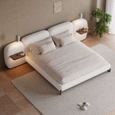 a white bed sitting in the middle of a bedroom next to a plant on top of a rug