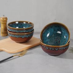 two bowls on a cutting board with utensils next to them and a wooden spoon