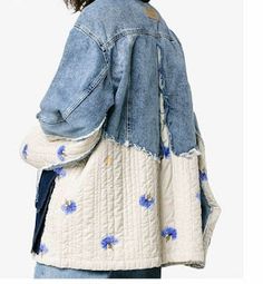 a woman wearing a jean jacket with blue flowers on the back and white quilting