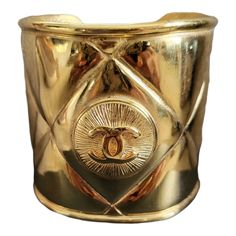 a gold colored metal container with an emblem on the front and bottom, in geometric design