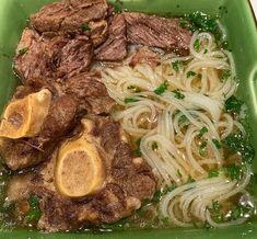 a green plate topped with meat and noodles