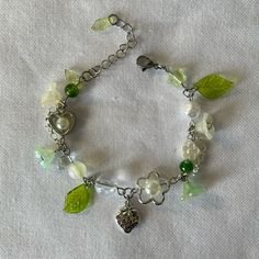 a green and white bracelet with charms on it's sides, sitting on a white cloth