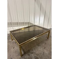 a glass and brass coffee table in the shape of a rectangle, with two legs