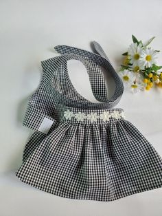 a black and white checkered dog dress next to some daisies on a white surface