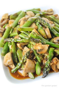 asparagus and mushrooms with sauce on a white plate