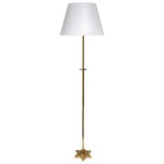 a gold floor lamp with a white shade on the base and a star shaped light