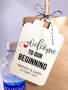 a welcome to our beginning sign hanging from a brown paper bag next to a bottle of water