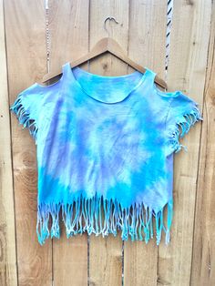 a blue tie dye top hanging on a wooden fence