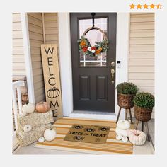 a welcome mat is on the front porch with pumpkins and other fall decorations around it