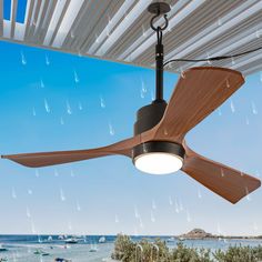 a ceiling fan that is hanging from a roof over the ocean and boats in the water