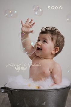 a baby sitting in a bucket with soap bubbles