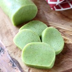 four pieces of green food sitting on top of a wooden cutting board