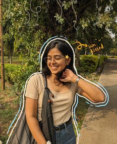 a woman standing in front of a tree with her hand on her hip and wearing glasses