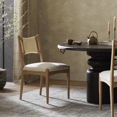 a dining table with two chairs and a potted plant in the corner next to it