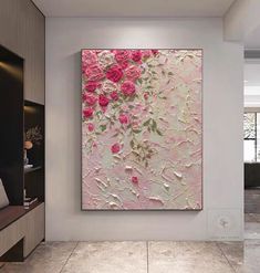 an abstract painting with pink flowers on a white wall in a modern living room setting