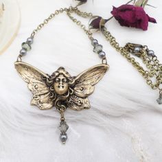 For this new handmade necklace I started with a stunning antiqued brass metal pendant, depicting a lovely butterfly goddess.  The details are truly lovely in hand.  This is a stamped pendant so it's HOLLOW on the back, as shown in the listing photos.  I have added sparkly Black Diamond first quality crystals, along with dark gray pearls, antiqued brass chain and findings, ending with a lobster clasp. The butterfly measures 2 inches wide and 1 inch tall.  The necklace is adjustable from 16 1/2 to 18 1/2 inches.  Thank you for taking the time to view and read, to see more please click here:  www.etsy.com/shop/hhjewelrydesigns Butterfly Goddess, Fairycore Jewelry, Ethereal Style, Fairy Goddess, Goddess Necklace, Antique Brass Metal, Butterfly Fairy, Pearl Grey, Metal Pendant