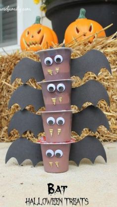 halloween decorations made out of toilet paper cups and bats on hay bales with pumpkins in the background