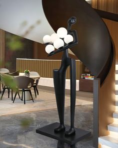 a black sculpture with three white balls on it's back legs and arms in front of a dining room table