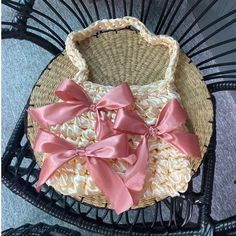 a wicker basket with pink bows sitting on top of a black metal chair next to a wall