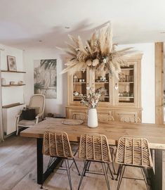 a dining room table with chairs and a vase filled with flowers on top of it