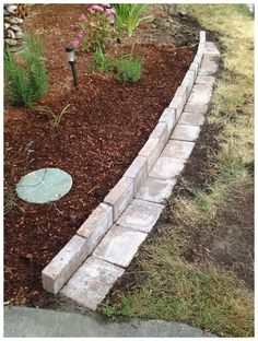 a brick garden border with mulch grass and flowers