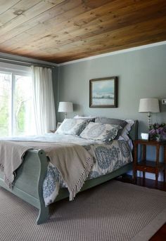 a bedroom with a large bed and wooden ceiling