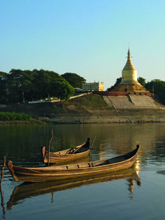 two small boats floating on top of a lake next to a large golden building in the background