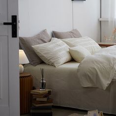 a bed with white sheets and pillows in a room