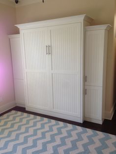 a bedroom with white closets and blue rug on the floor in front of it