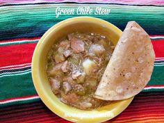 a yellow bowl filled with soup next to a tortilla on top of a colorful table cloth