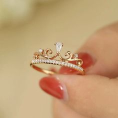 a woman's hand holding a gold ring with diamonds