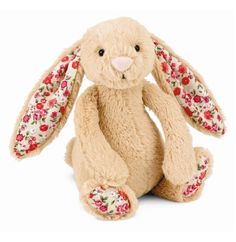 a stuffed rabbit with floral fabric on it's ears, sitting in front of a white background