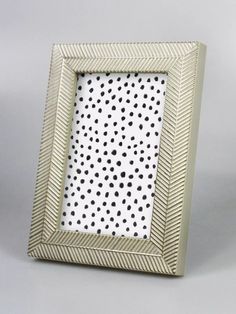 a white and black photo frame with polka dots on the front, sitting on a table