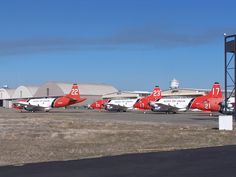 several red and white airplanes are parked on the tarmac