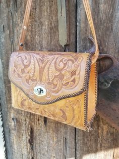 Whether you're a cowgirl or a western boho chic Fashionista, this vintage tooled leather purse is an accessory you need. I can only imagine the hours that went into stamping this mid-century heavy stamped leather purse. The exterior is the natural leather with the tooling done on the flap, front and back of the purse. The interior is dark brown. It does show age and wear. There are 2 interior pouches on this 1960s cowgirl purse. The strap on this tool leather purse is not quite long enough to be a crossbody. it does have a snap on this purse forming a small Loop perfect for your key ring. This vintage hand stamped leather purse measures approximately 9 in wide at its widest point. it stands 7 in in height and is approximately 3.5 in depth at the base. It is important to note that some of t Luxury Vintage Hand Tooled Bag, Luxury Hand Tooled Vintage Bags, 1960s Cowgirl, Western Purses And Handbags, Western Leather Purse, Cowgirl Purse, Thrift Bundle, Western Bags Purses, Western Bags