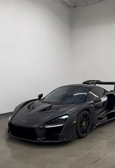 a black sports car parked in a large room with no one around it and the door open