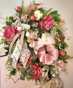 a wreath with flowers and ribbons hanging on the wall