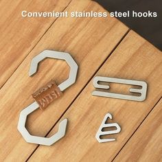 some metal tools are laying on a wooden table with the words convenient stainless steel hooks